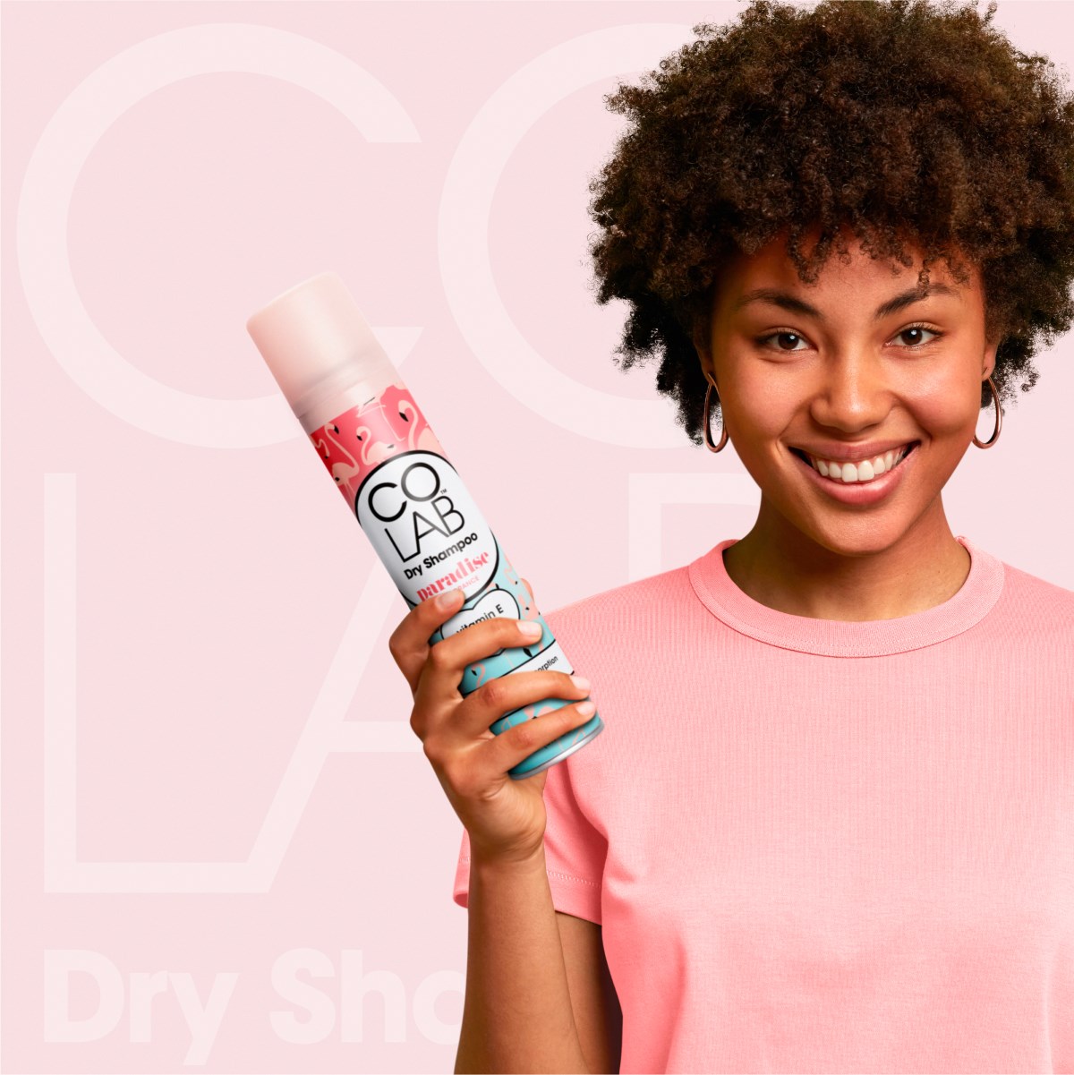 Model with an afro holding a can of COLAB Paradise 200ml Dry Shampoo